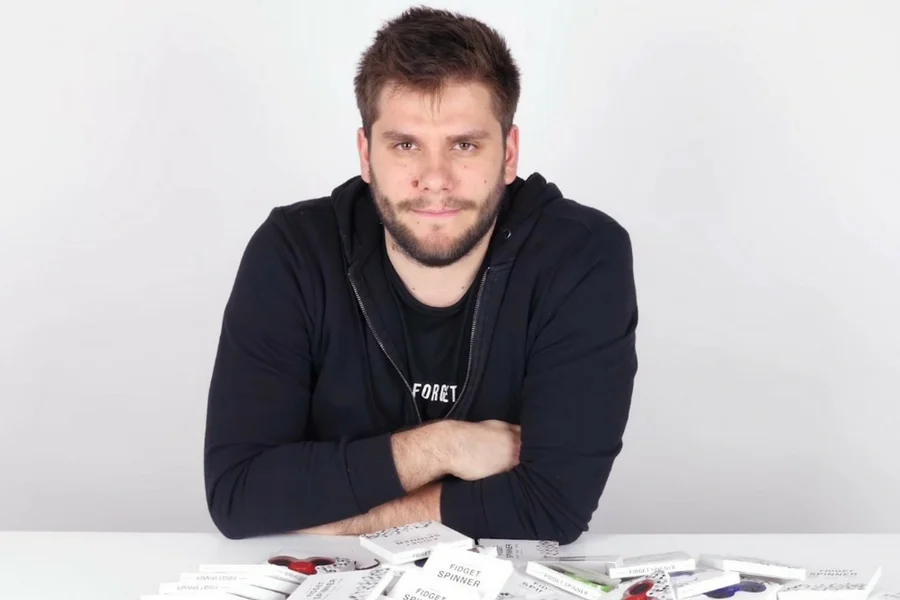 Adam, youtuber znany jako Poszukiwacz, rozpakowuje pudełko ze stosem fidget spinnerów.