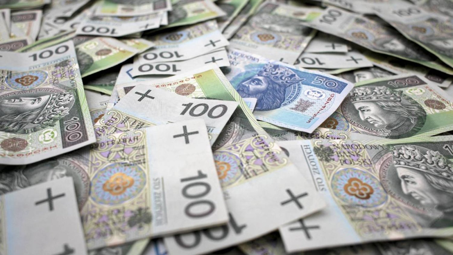 Pieniądze. Banknoty 100- i 50-złotowe na stole.