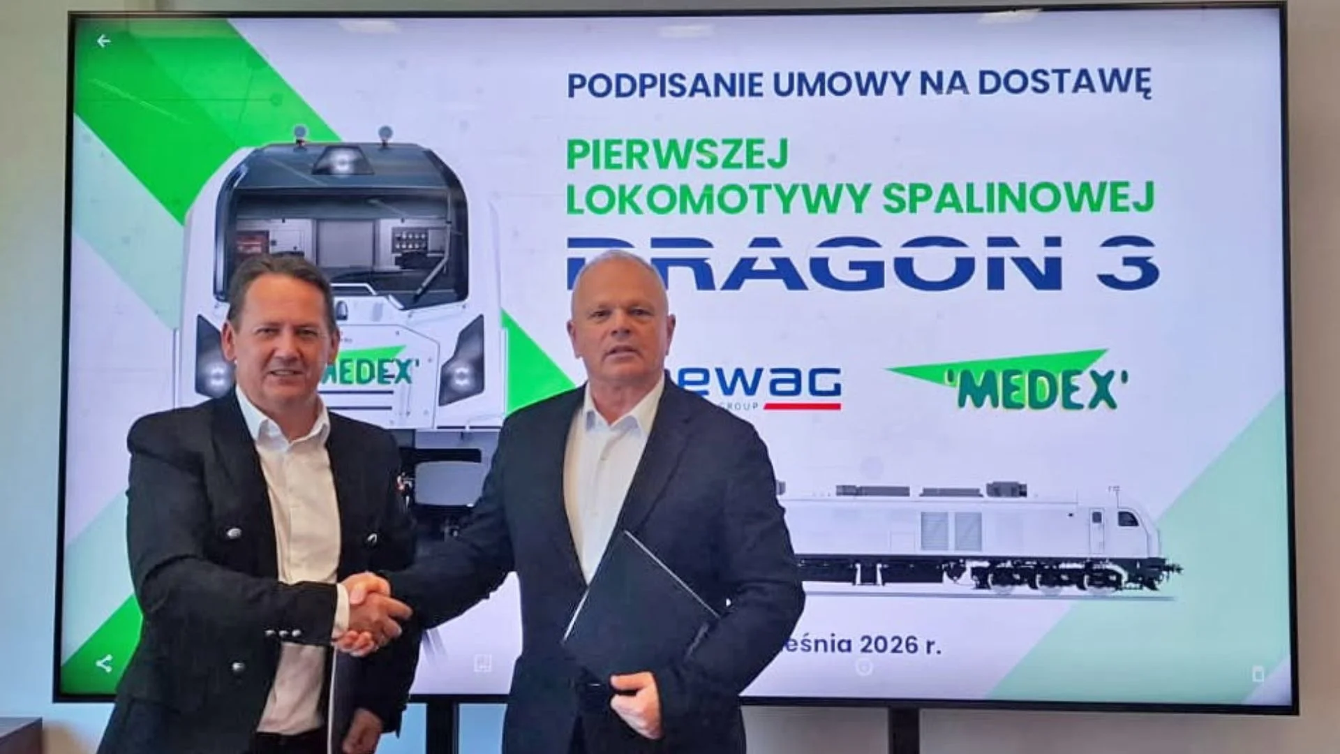 Pierwsza taka maszyna od 40 lat. Polski Newag znów zbuduje potężną lokomotywę spalinową. Dwóch mężczyzn na tle tablicy.