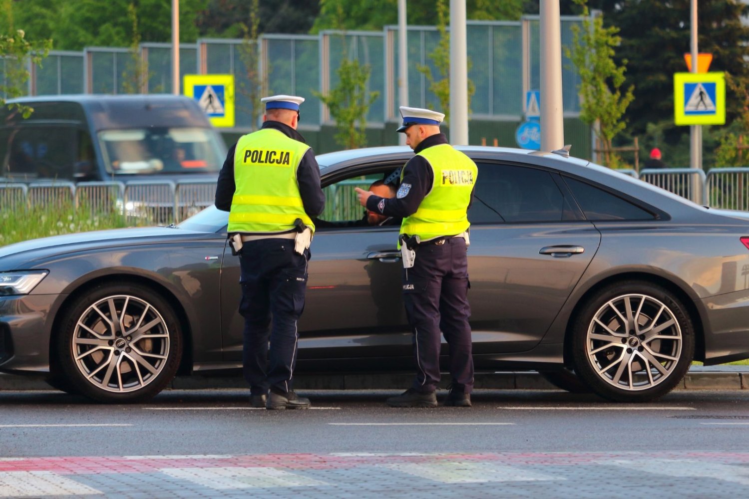 Historyczny rekord na polskich drogach. Tego jeszcze nie było. Dwóch policjantów stoi przy samochodzie na drodze.