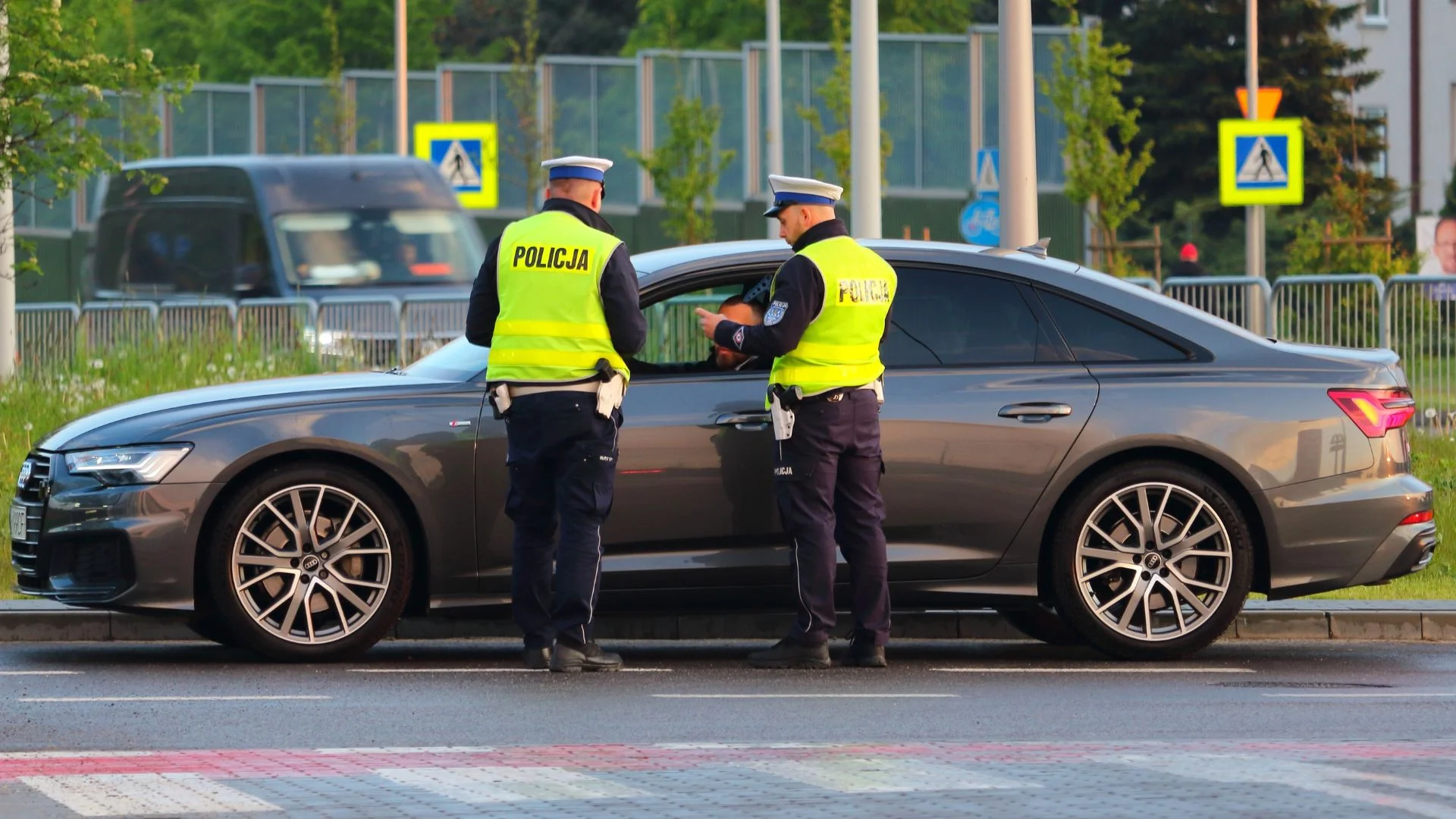 Historyczny rekord na polskich drogach. Tego jeszcze nie było. Dwóch policjantów stoi przy samochodzie na drodze.