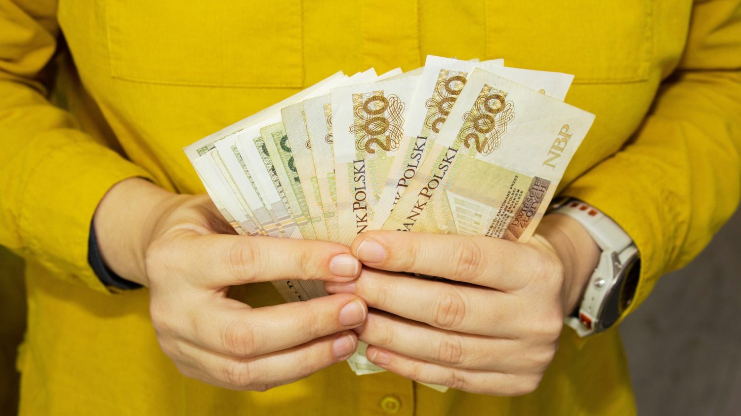 Człowiek z polskimi banknotami w rękach. Ile gotówki można wypłacić od ręki? PKO, Pekao, ING i inne banki mają bardzo różne limity