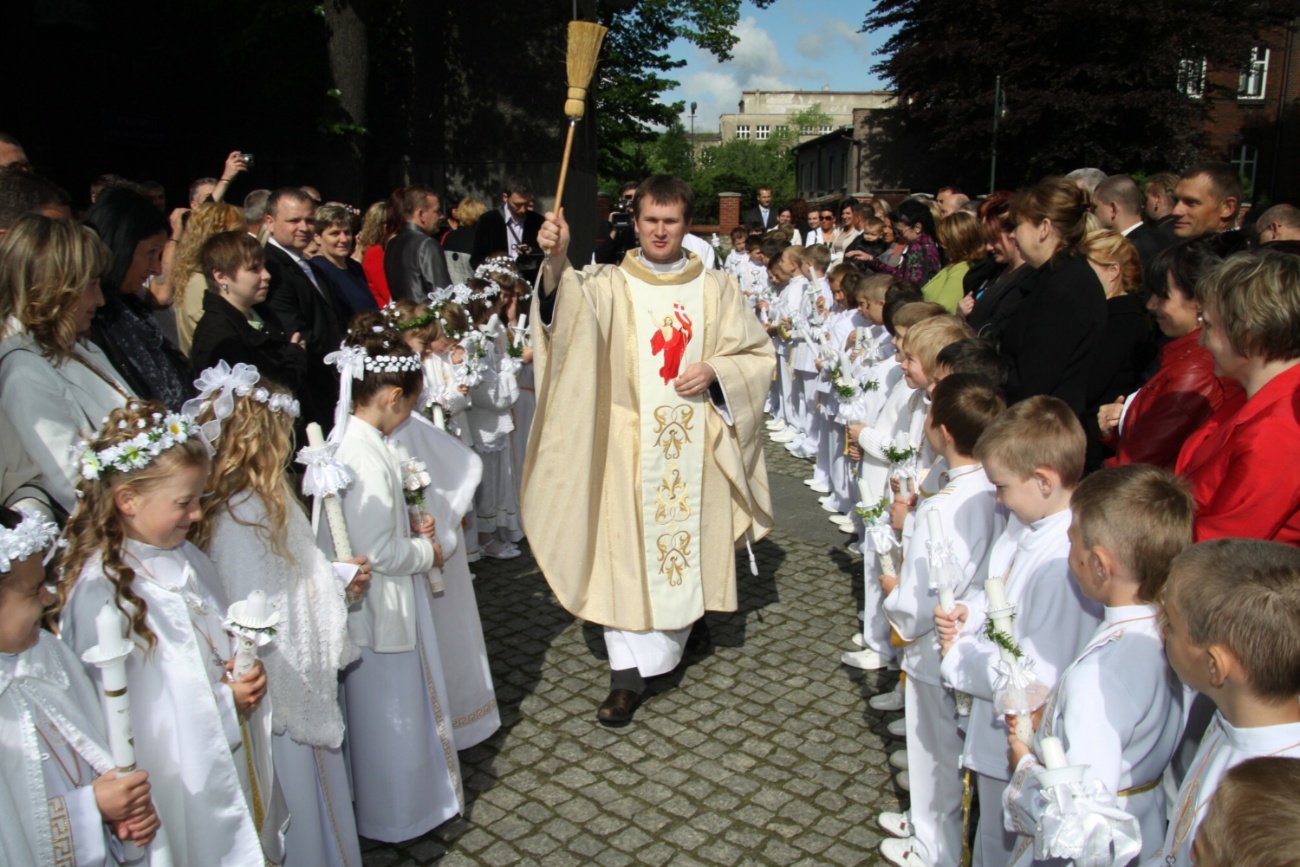Ksiądz i dzieci przystępujące do pierwszej komunii świętej.
