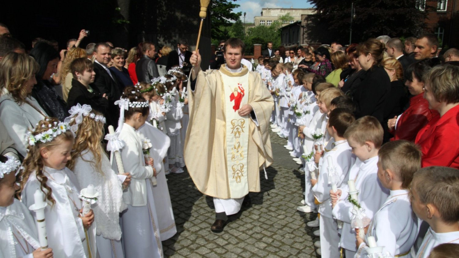 Ksiądz i dzieci przystępujące do pierwszej komunii świętej.