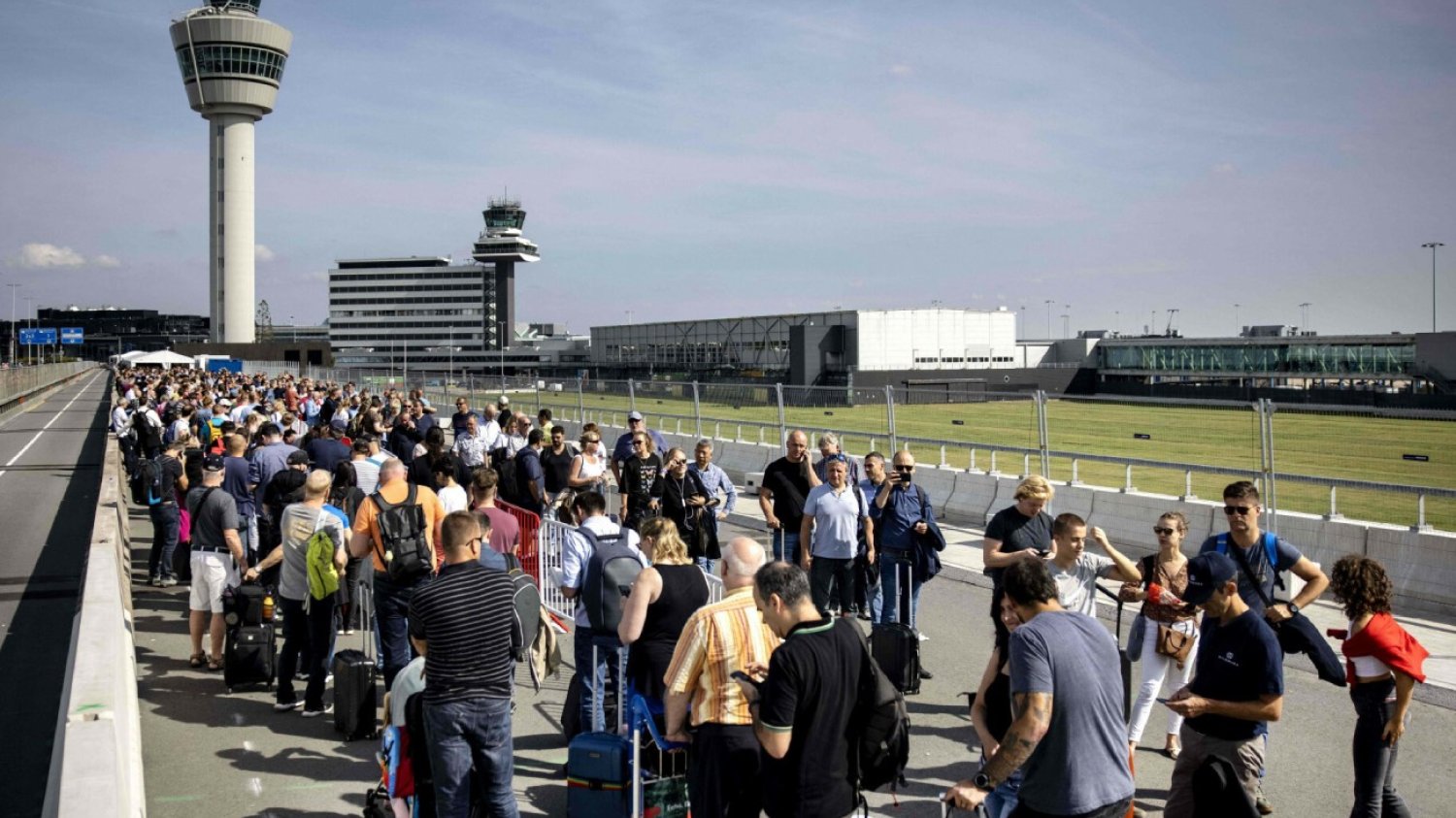 Kolejka pasażerów przed lotniskiem Schiphol w Amsterdamie