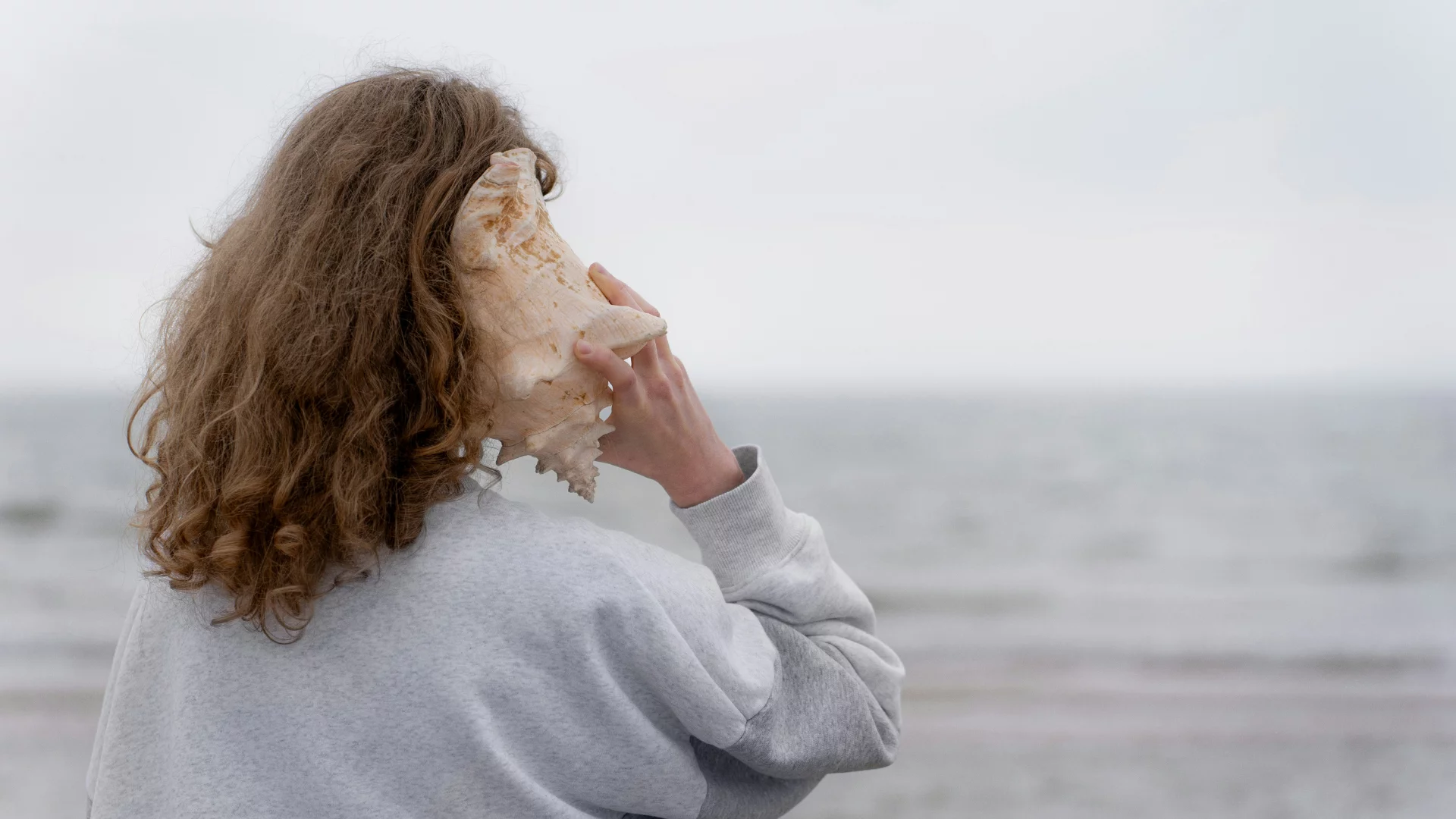 Kobieta przykłada muszlę do ucha. Wystarczy spacer, by wyostrzyć słuch