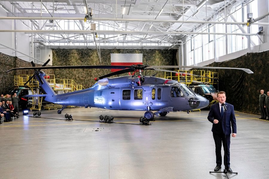 Minister obrony Mariusz Błaszczak na tle zakupionych śmigłowców Black Hawk S70i. Dopuścił się kilku nieprawdziwych stwierdzeń. To nie śmigłowiec gotowy do boju, a szkielet, wymagający dalszych modyfikacji. W dodatku nie powstaje w całości w Polsce - w Mie