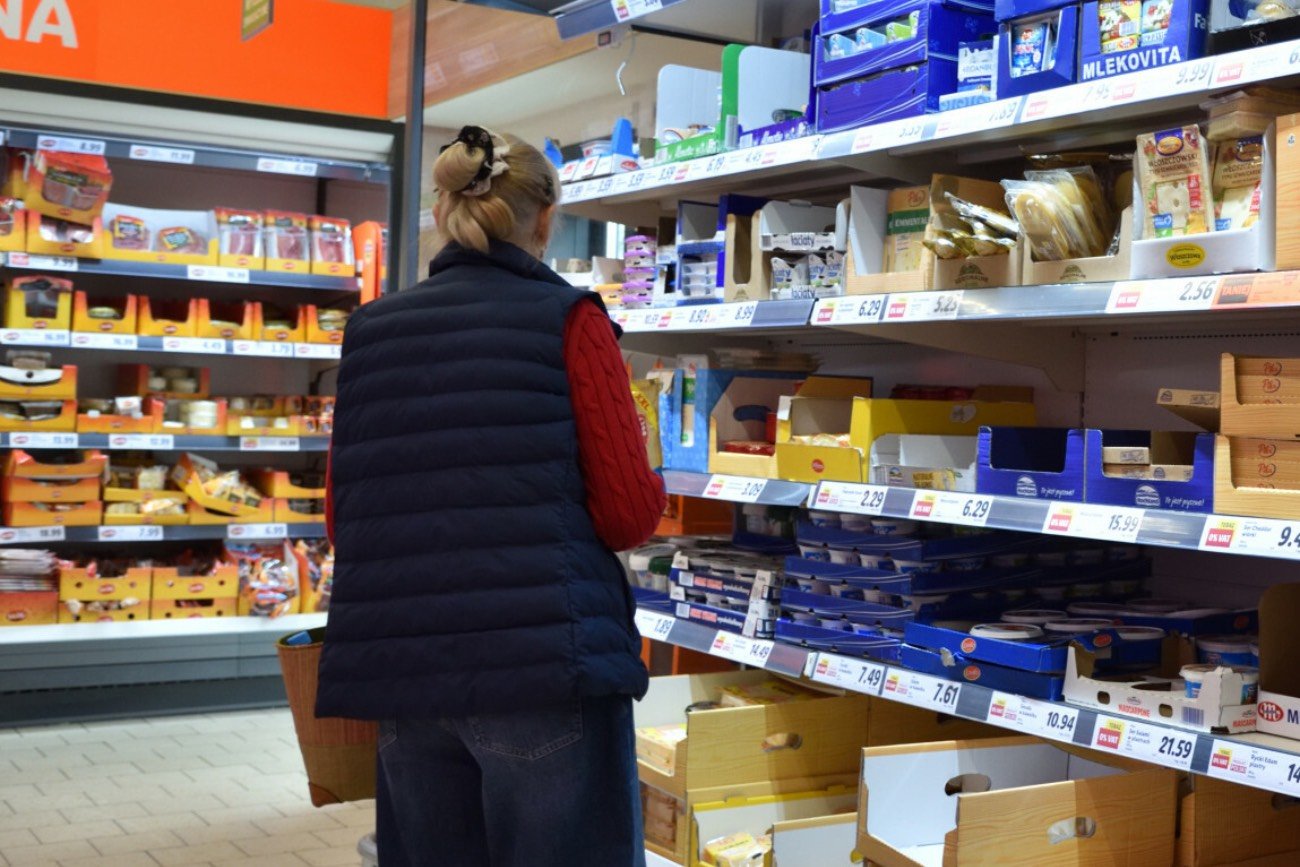 Kobieta na zakupach przed lodówką w sklepie