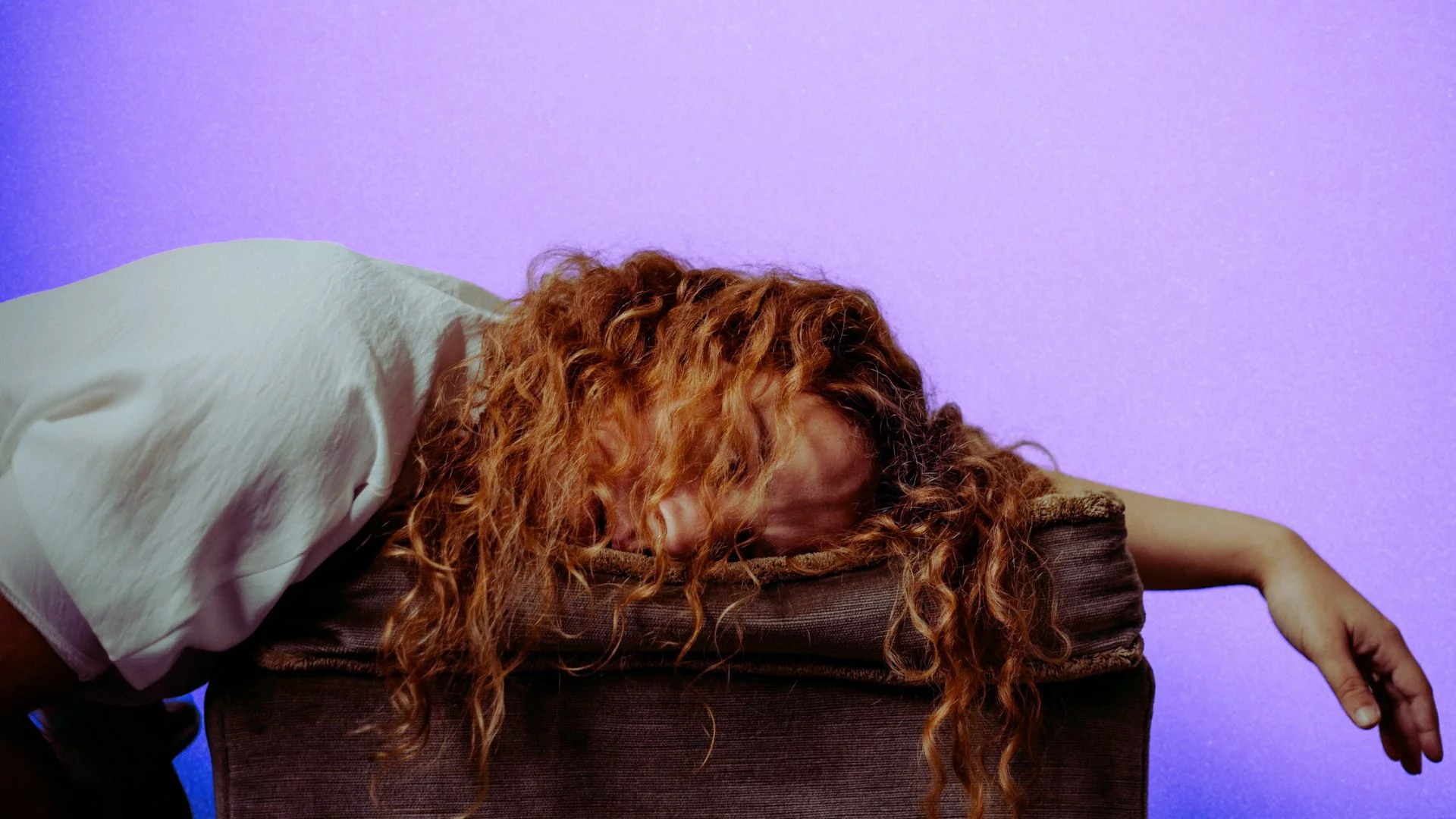 Wykończona kobieta śpiąca z głową na wyciągniętej ręce.