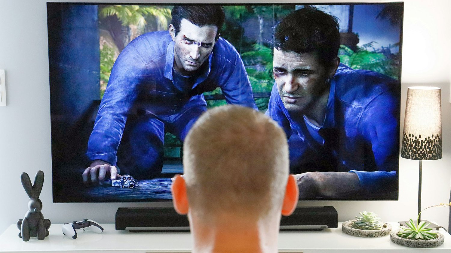mężczyzna oglądający telewizję, na ekranie dziwne męskie postacie