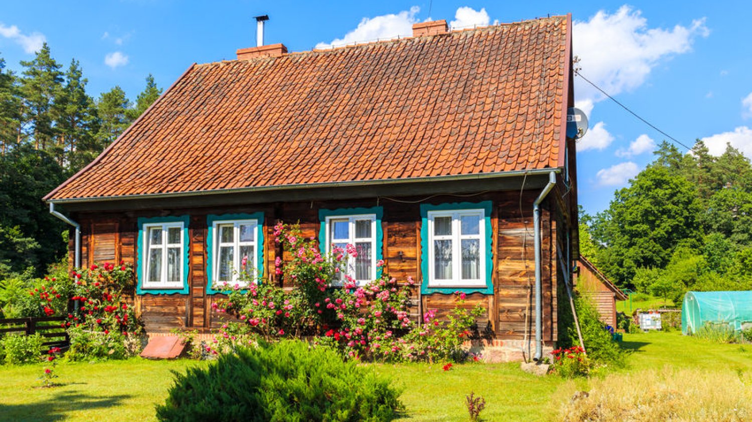 Rustykalny Mazurski domek drewniany z niebieskimi okiennicami.