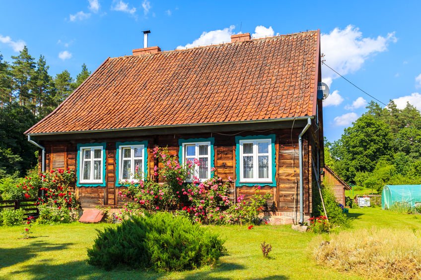 Rustykalny Mazurski domek drewniany z niebieskimi okiennicami.