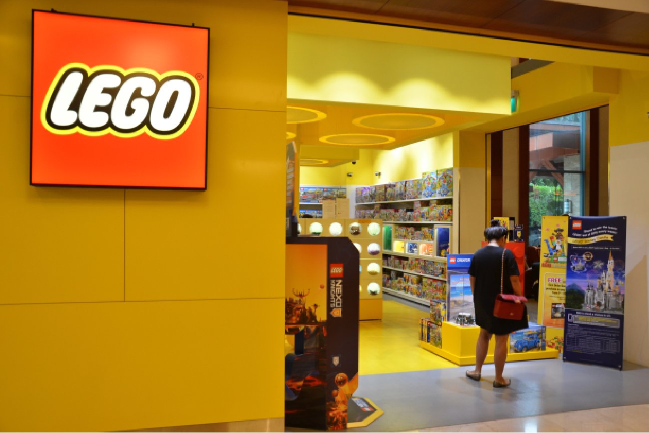 witryna popularnego sklepu w czerwono-żółtych kolorach marki którego klientką jest młoda kobieta wchodząca do sklepu lego