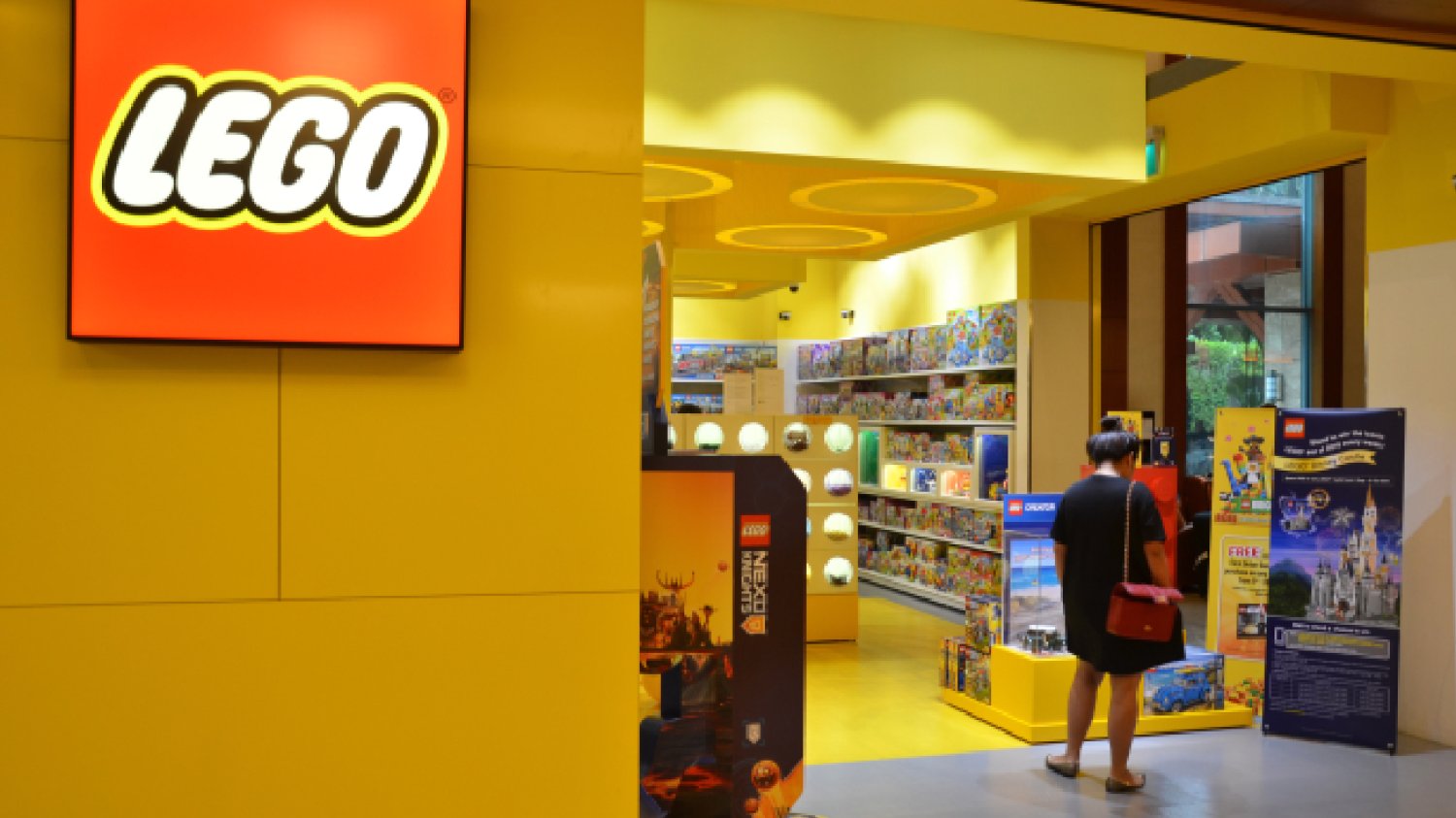witryna popularnego sklepu w czerwono-żółtych kolorach marki którego klientką jest młoda kobieta wchodząca do sklepu lego