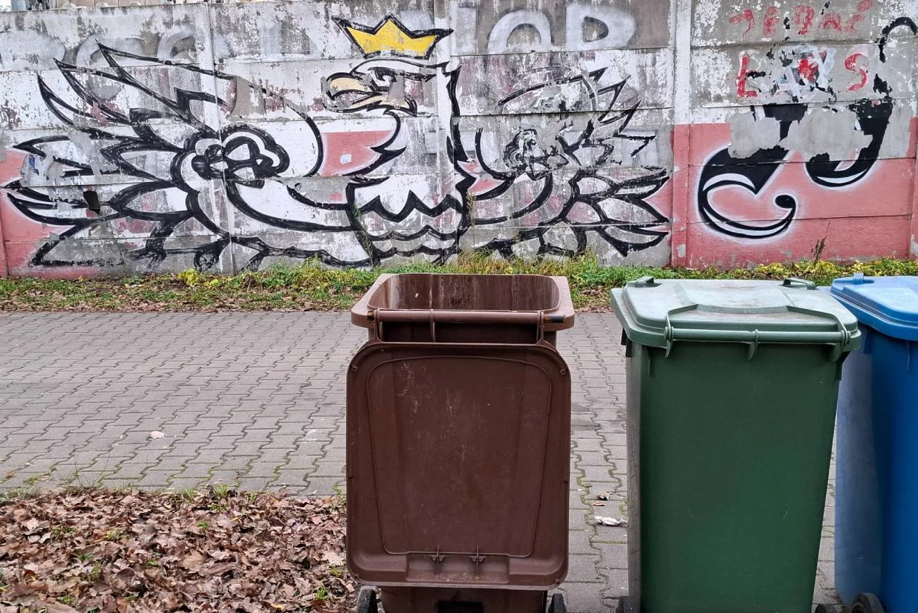Kosze na odpady na tle muralu.