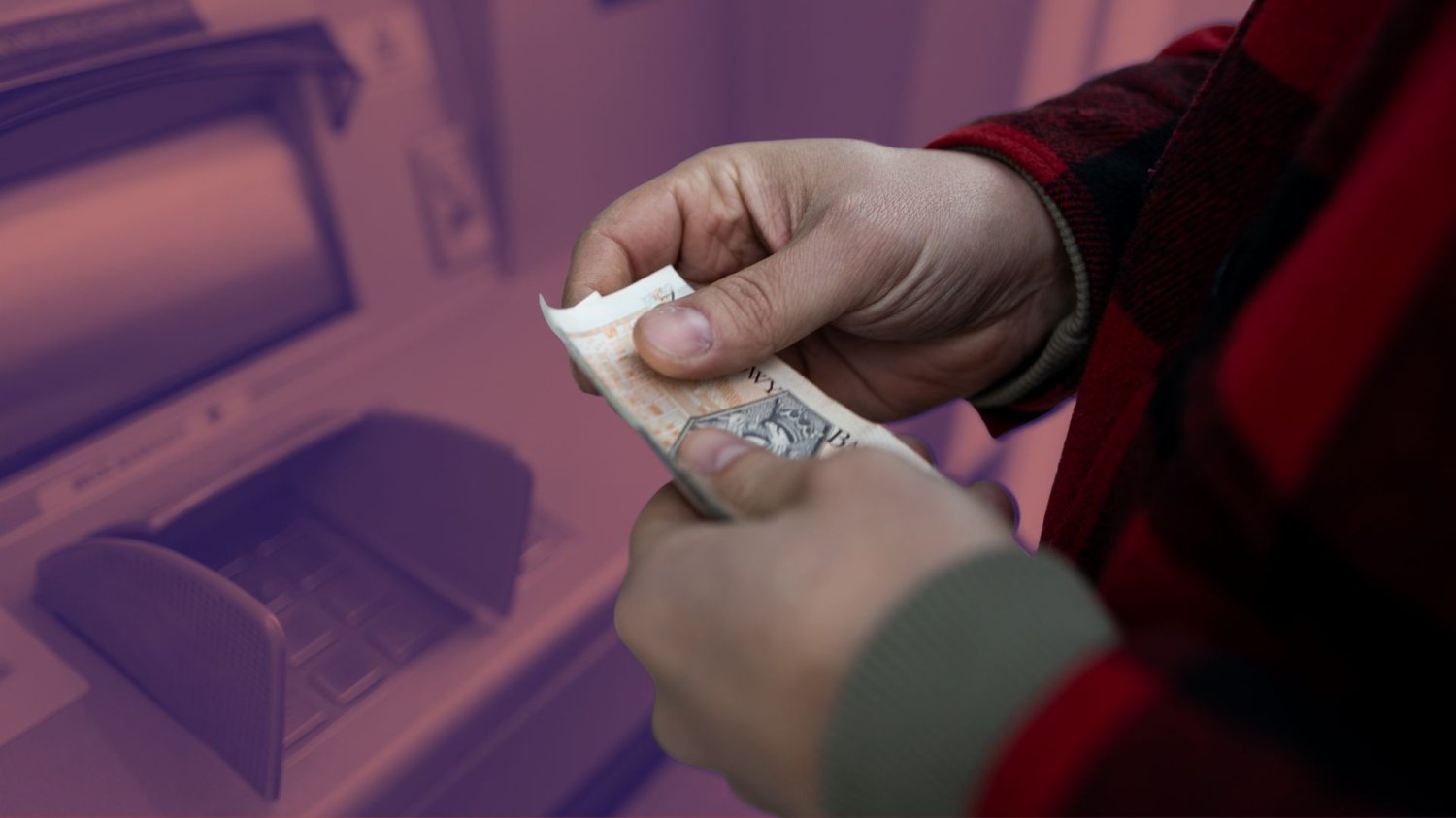 Mężczyzna wypłacający gotówkę w bankomacie. Visa i Mastercard podniosą za to prowizję.