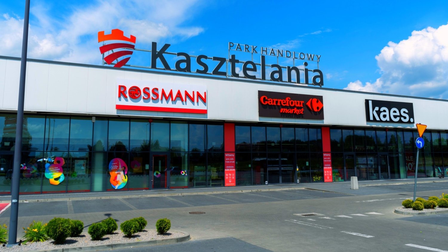 Wejście do budynku parku handlowego w Chrzanowie. Na elewacji nazwy sklepów.