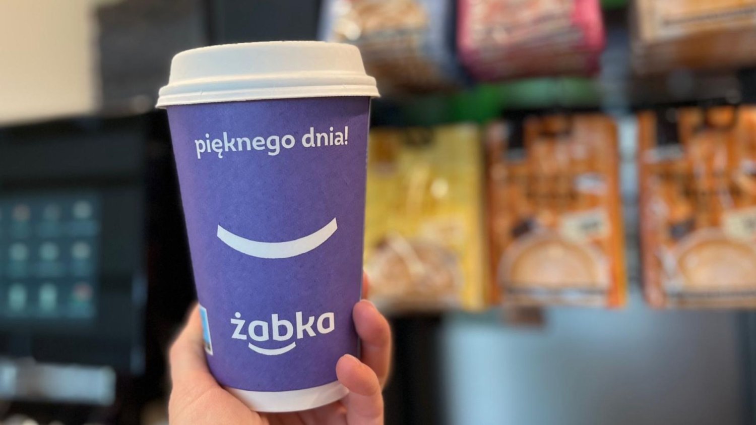 Fioletowy papierowy kubek z kawą od Żabki.
