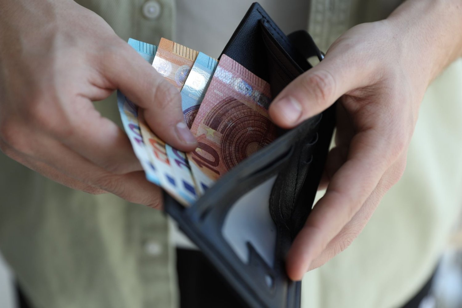 Człowiek trzyma portfel z banknotami euro. Tak mogą wyglądać nowe banknoty euro. Wśród nich polska noblistka