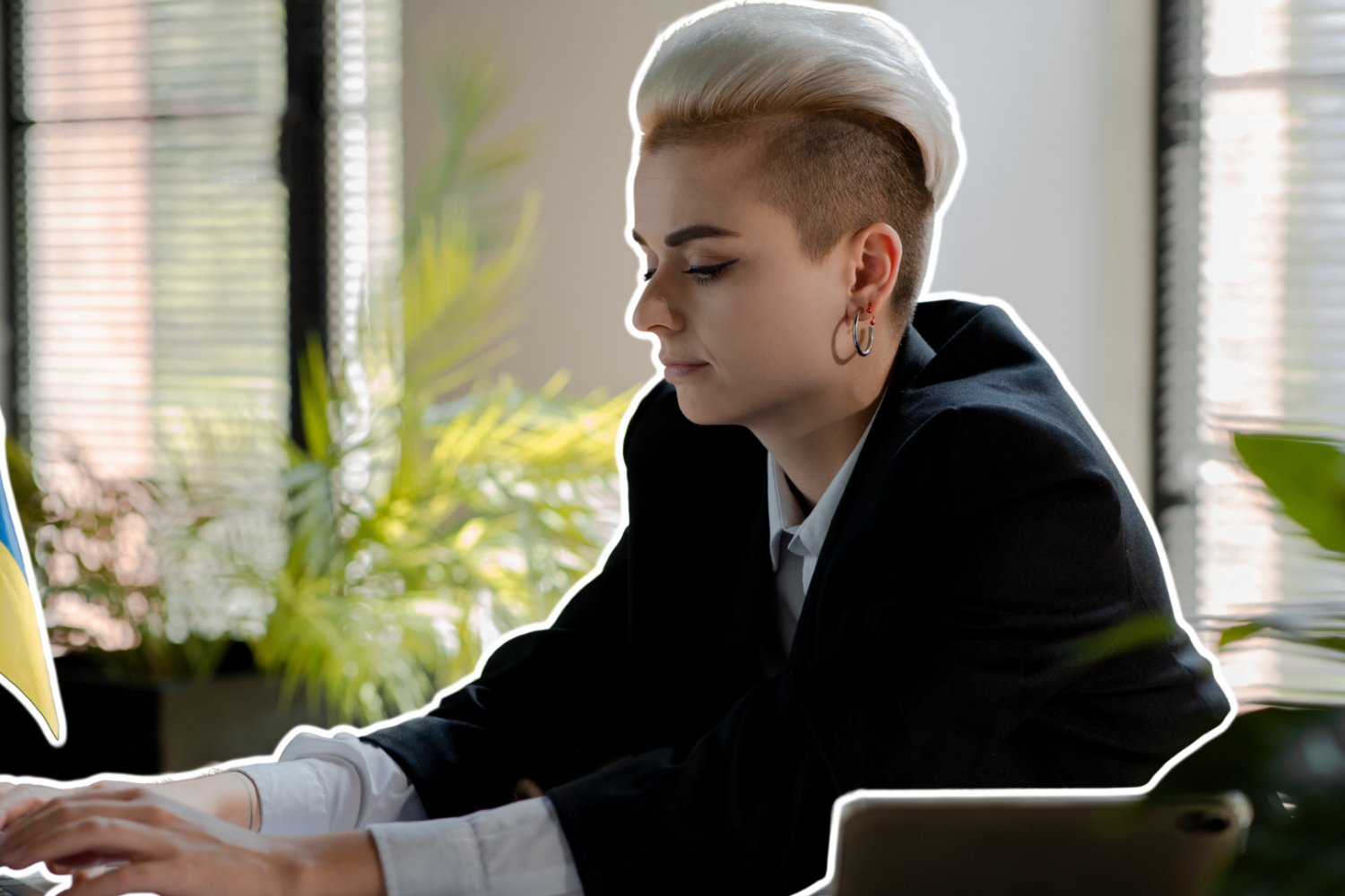 Kobieta, business woman, pracuje. Na biurku przed nią jest flaga Ukrainy.