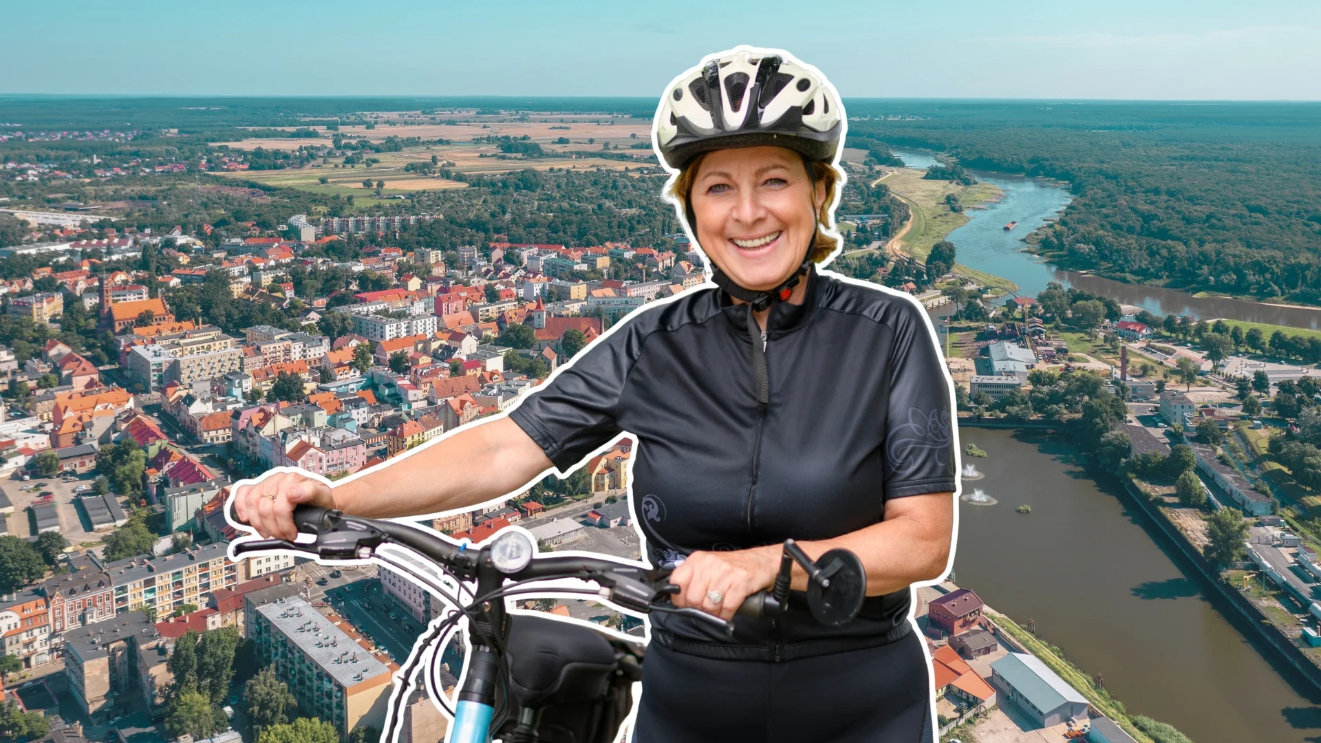 Kobieta z rowerem, uśmiechnięta. W tle panorama miejscowości Nowa Sól