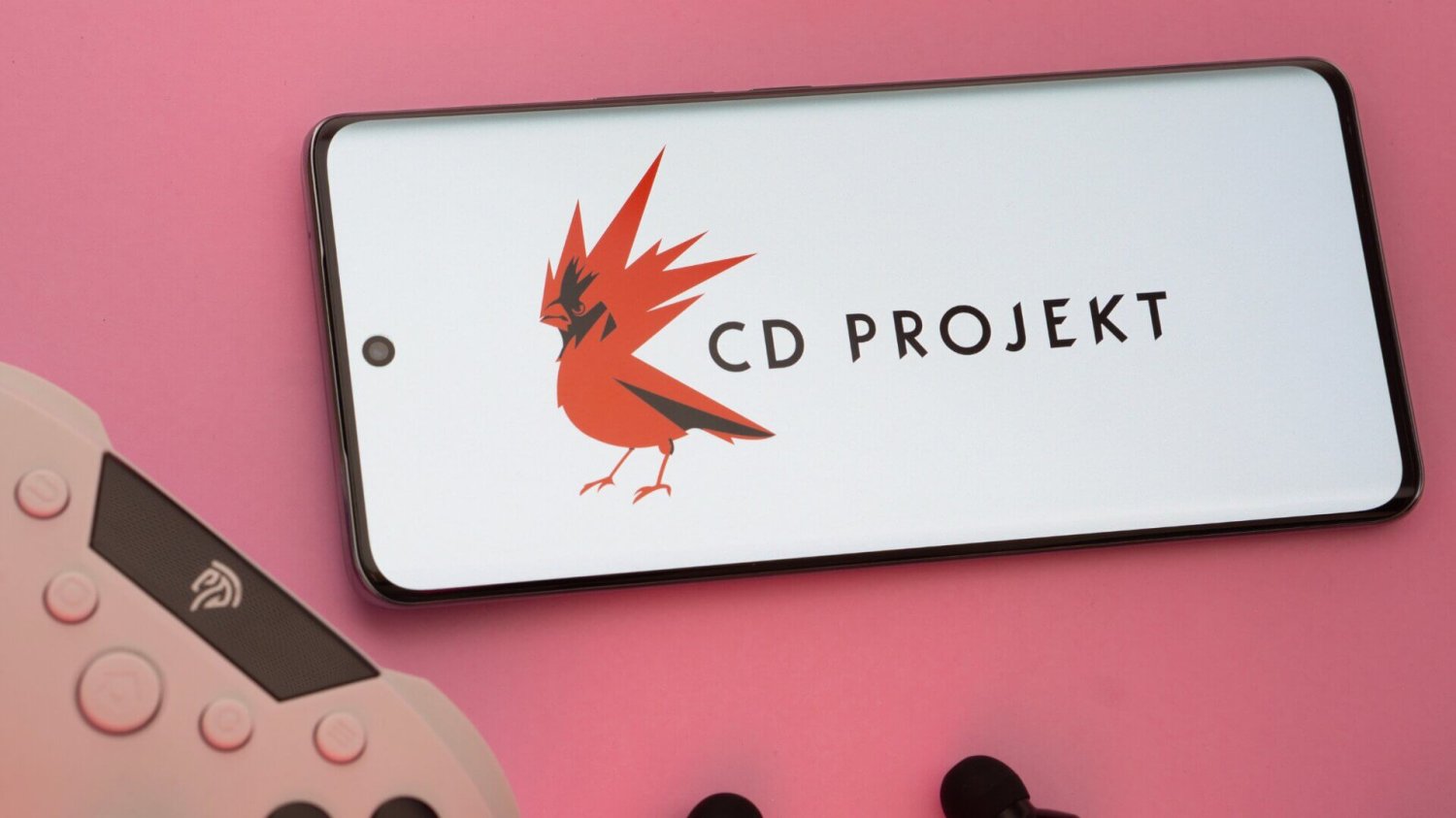 logo CD Projekt na smartfonie, obok pad do konsoli