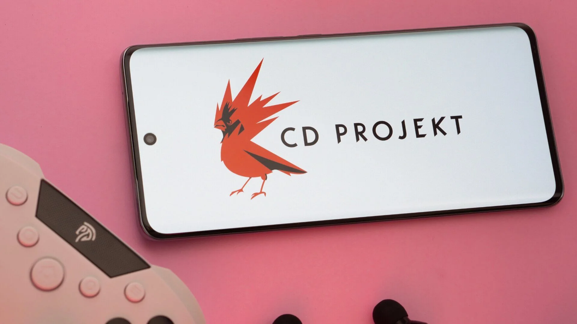 logo CD Projekt na smartfonie, obok pad do konsoli