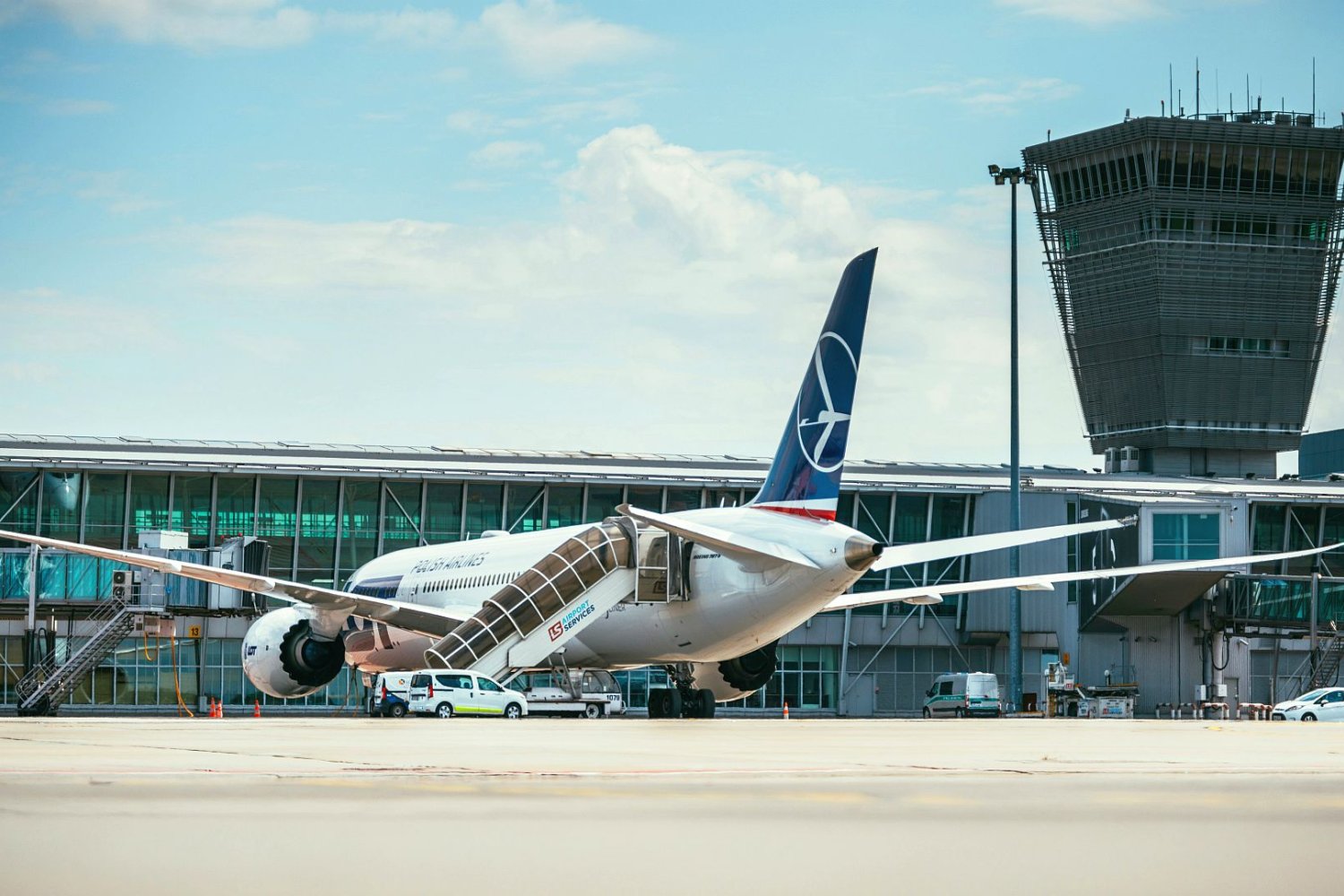 Lotnisko Okęcie. Na pierwszym planie samolot na płycie lotniska, na drugim terminal.