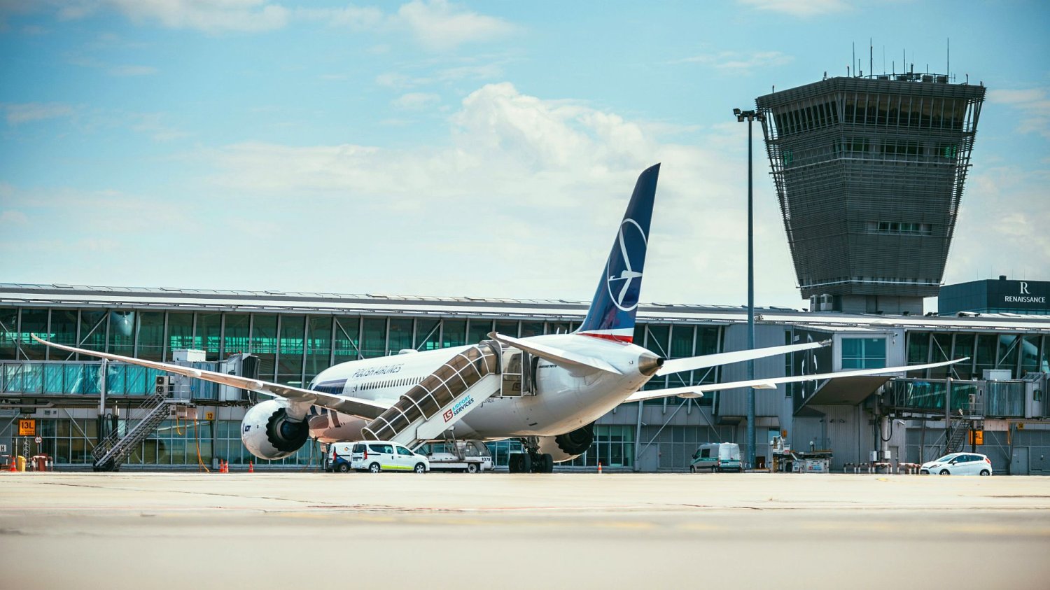 Lotnisko Okęcie. Na pierwszym planie samolot na płycie lotniska, na drugim terminal.