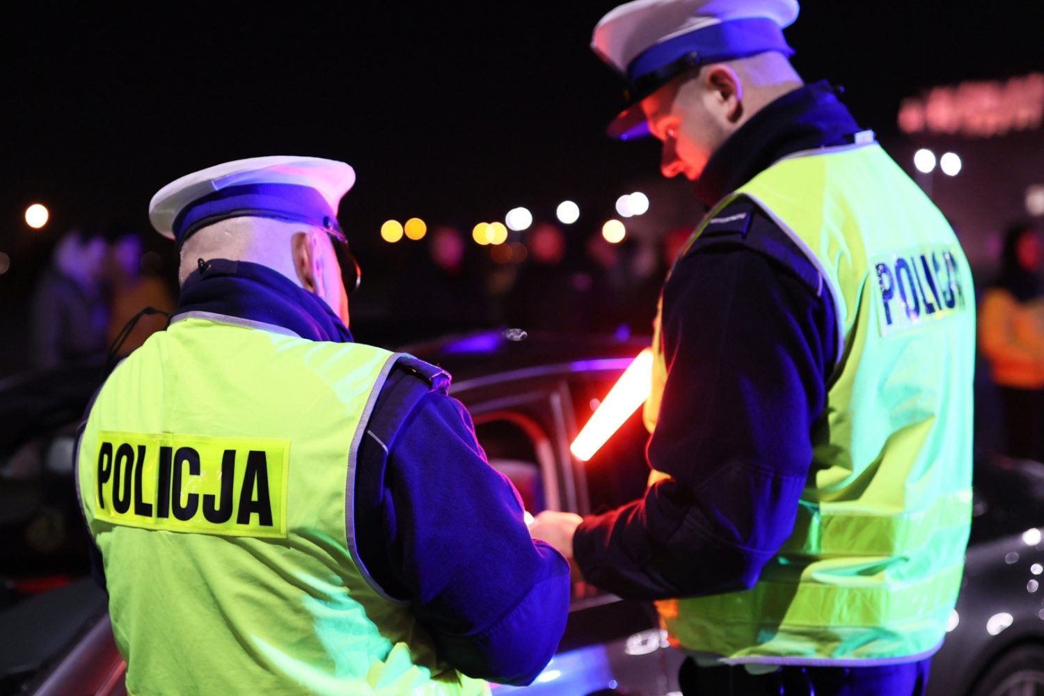 Kontrola policyjna. Dwóch policjantów w kamizelkach odblaskowych z napisem policja.