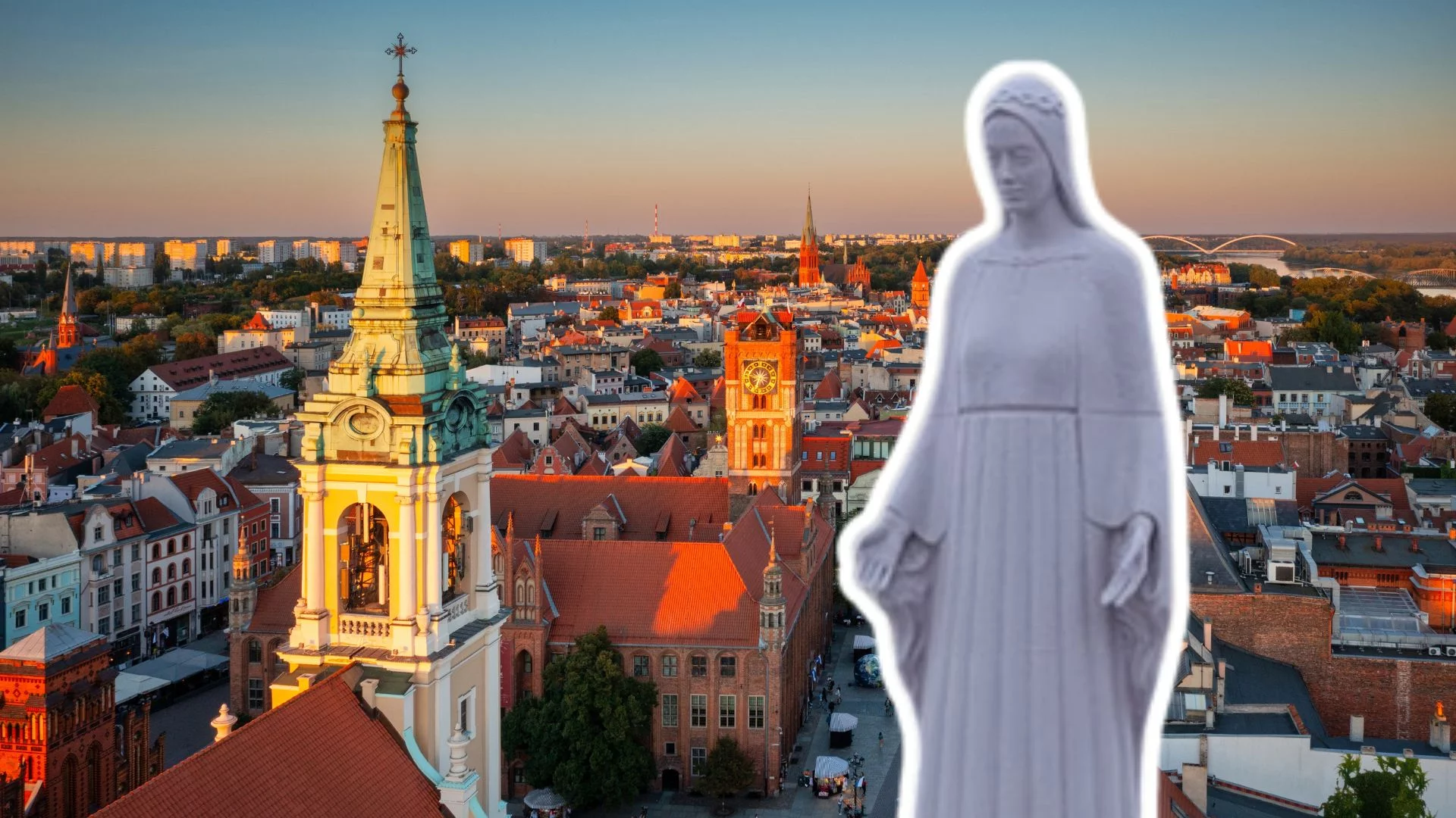 Makieta pomnika Matki Boskiej na tle panoramy Torunia.