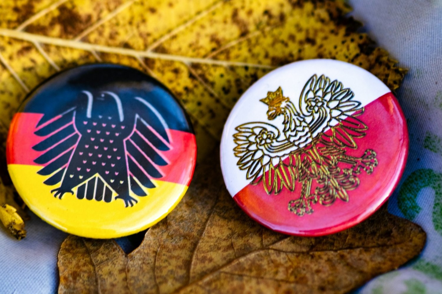 Okrągłe przypinki z symbolami Niemiec i Polski.