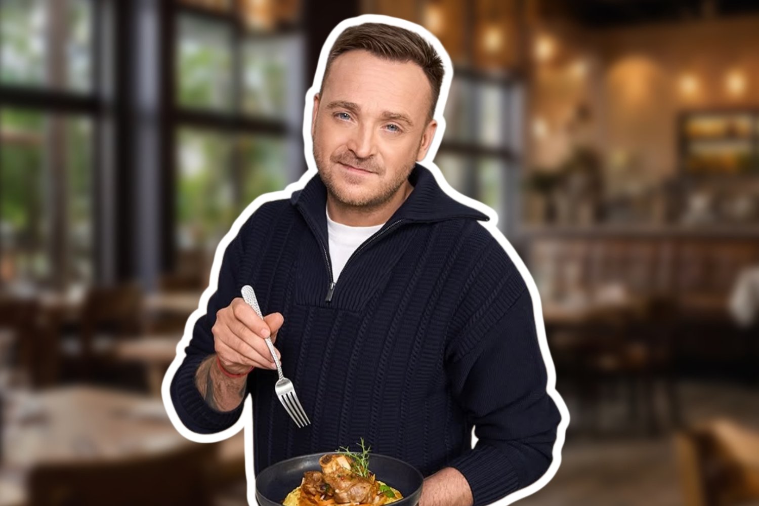 Mateusz Gessler trzymający talerz z daniem i widelec. W tle zablurowana restauracja.