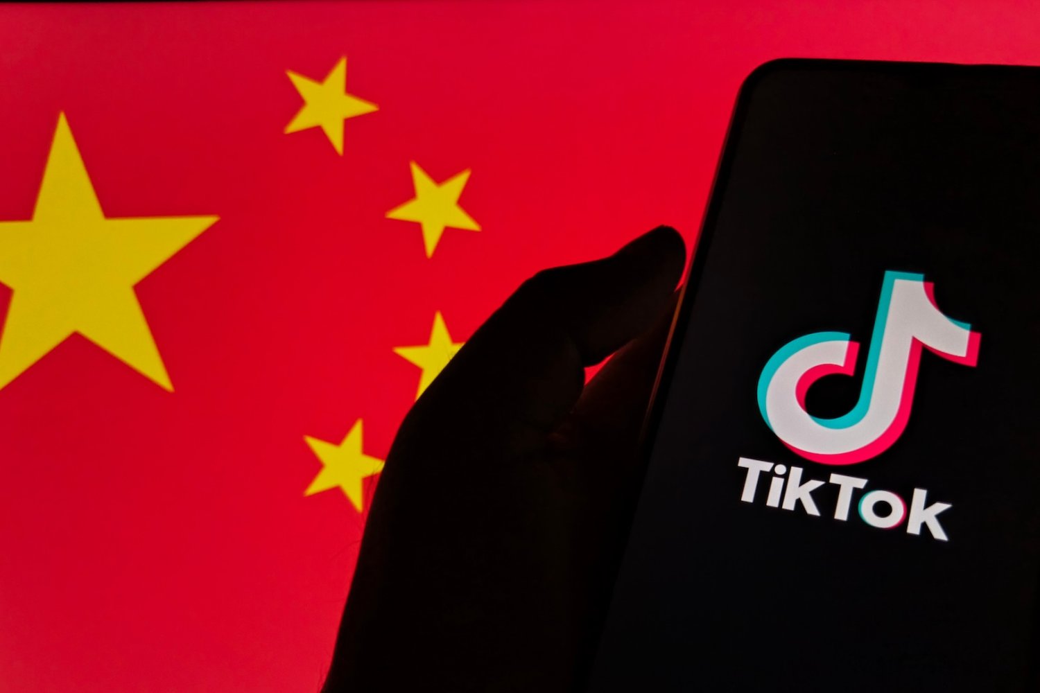 Smartfon wyświetlający logo TikToka na tle flagi Chin.