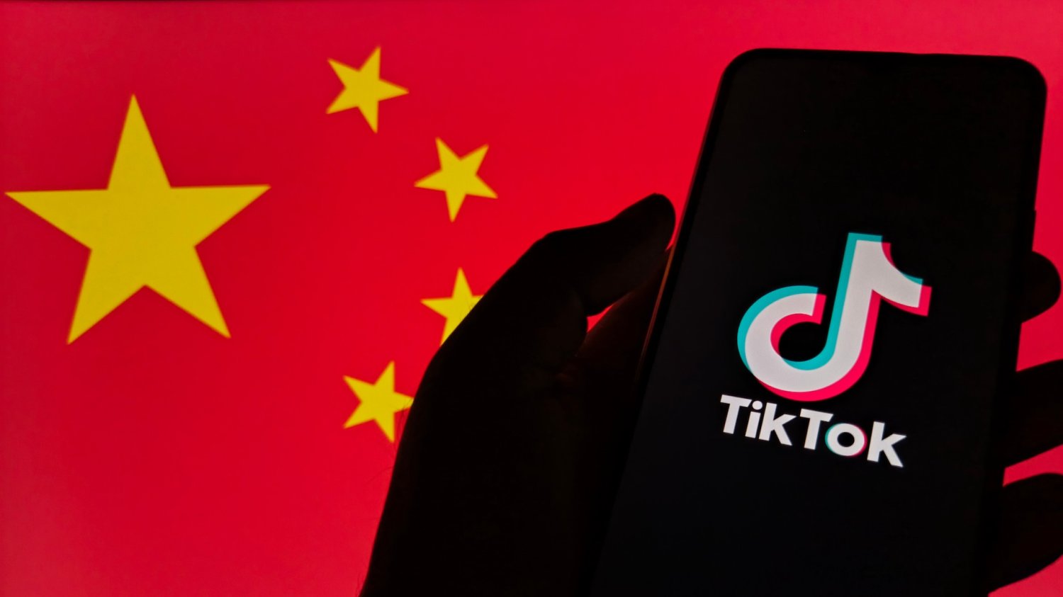 Smartfon wyświetlający logo TikToka na tle flagi Chin.