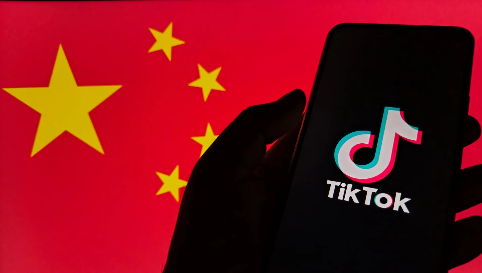 Smartfon wyświetlający logo TikToka na tle flagi Chin.