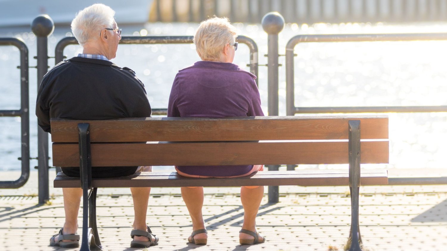 ZUS apeluje do seniorów. Taka emerytura chroni Twoje pieniądze przed złodziejami Starsza para siedząca na drewnianej ławce nad morzem. Emerytura bezpieczna od złodziei. Ważny komunikat ZUS do seniorów