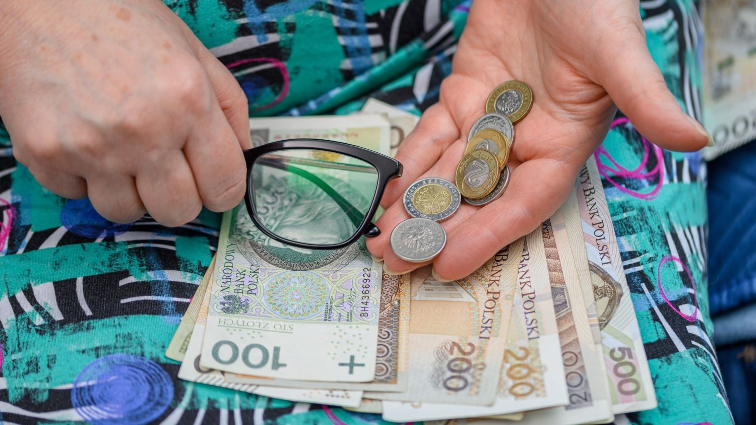 ZUS przeliczy emerytury tysiącom seniorów. Nawet 552 zł więcej, ale jest haczyk Starszy człowiek trzymający pieniądze i okulary