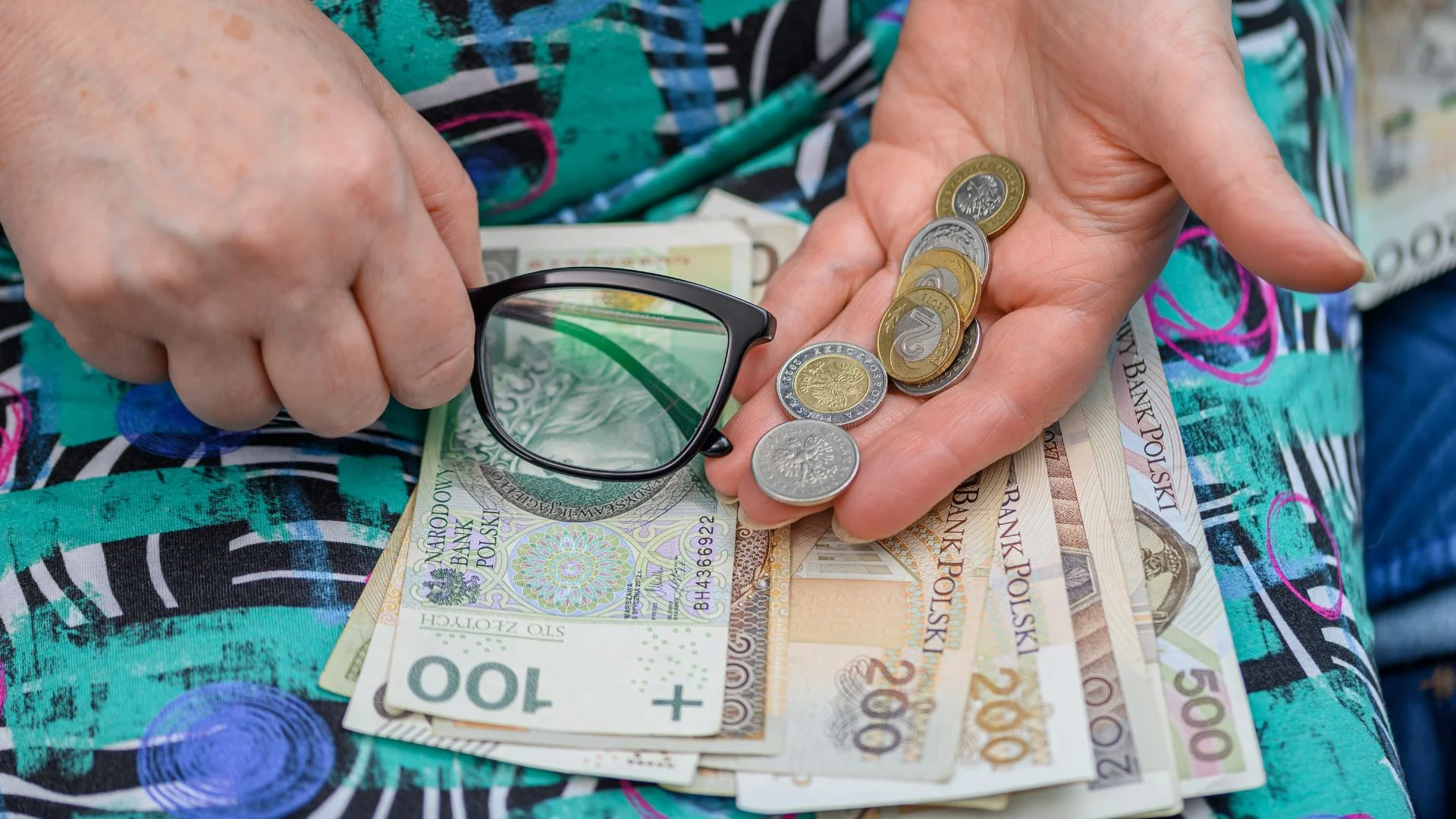 ZUS przeliczy emerytury tysiącom seniorów. Nawet 552 zł więcej, ale jest haczyk Starszy człowiek trzymający pieniądze i okulary
