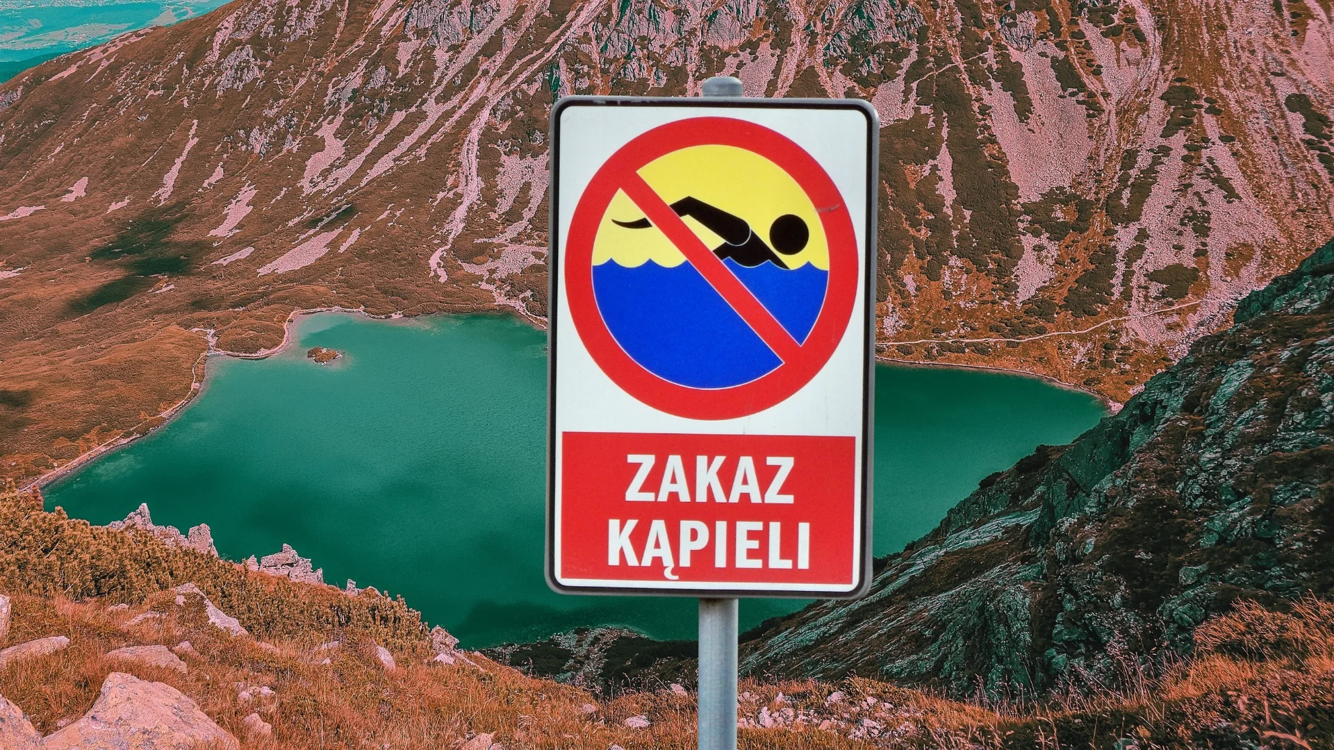 znak zakaz kąpieli na tle tatrzańskiego jeziora